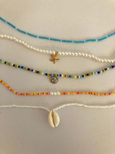 three necklaces with shells and beads on them