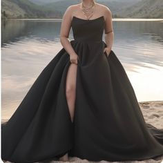 a woman in a black dress posing on the beach