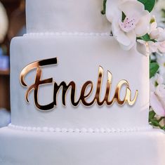 a white cake with gold lettering and flowers