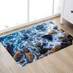 a rug with rocks and water on the floor in front of a white cabinet next to a window