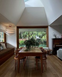 a dining room table with chairs and a potted plant on top of it in front of a large window