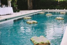 an outdoor pool with tables and chairs set up in the water for a wedding reception