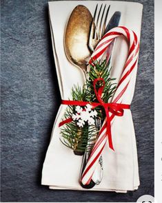 a fork, knife and spoon wrapped in christmas ribbon