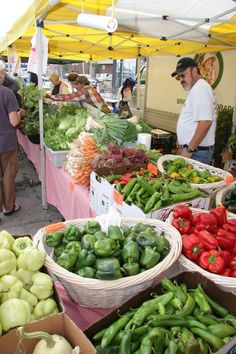 people shopping at an open air market with lots of vegetables