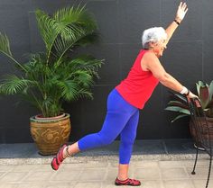 an older woman is doing exercises in front of a potted plant