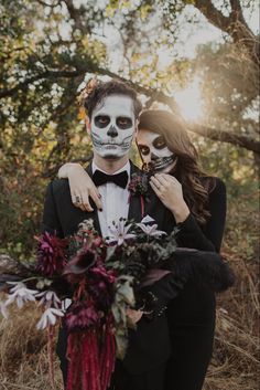 a couple dressed up in skeleton makeup and holding each other's head with flowers