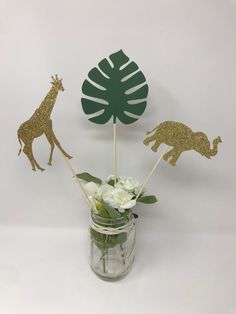 a vase filled with white flowers and gold foil giraffes on top of it