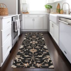 a kitchen area with white cabinets and black rug on the wooden floor next to stove top oven