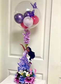 a balloon filled with purple and white flowers next to a glass ball on top of a table