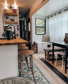 a kitchen and dining area in an rv with wood flooring, white walls and windows