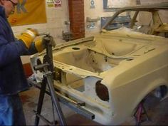 a man working on an old car in a garage