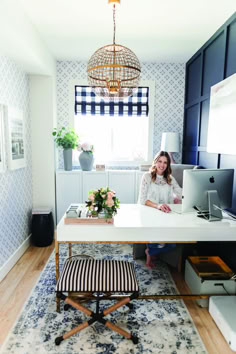 a woman sitting at a desk in front of a laptop computer on top of a rug