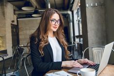 a woman sitting at a table working on her laptop