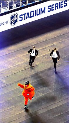 three people in orange and black outfits skating on the ice