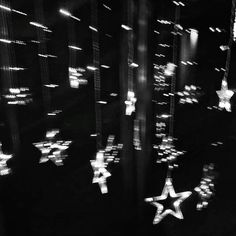 black and white photograph of stars hanging in the air at night with lights reflecting off them