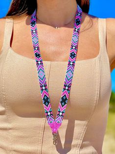 a woman wearing a tan tank top and pink beaded necklace with a blue sky in the background