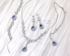 a necklace and earring set with blue stones on a white fabric background for an elegant bridal look