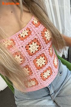 a woman with blonde hair wearing a pink and white crochet top sitting in a chair