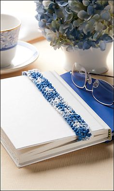 an open book with blue sprinkles on it sitting next to a cup and saucer