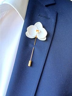 a white flower is attached to a blue suit lapel pin on a man's shirt