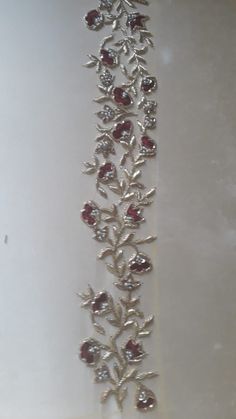 a silver bracelet with red stones and leaves