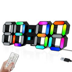 a person holding a remote control in front of an alarm clock that is multicolored