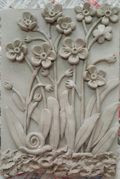 a clay sculpture with flowers and leaves on it