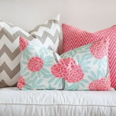 pillows on a white couch with chevroned chevrons and pink flowers in the center