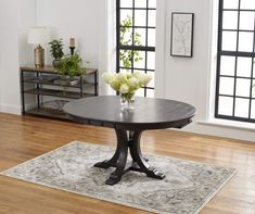 a dining room table with flowers on it in the middle of a wooden flooring area