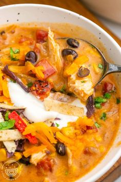 a white bowl filled with chicken and black bean soup on top of a wooden table