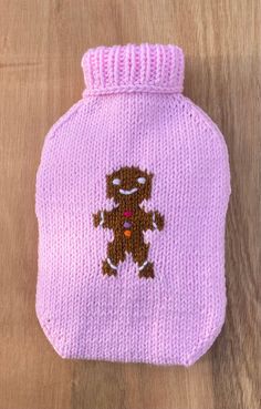 a pink knitted hot water bottle with a brown teddy bear embroidered on the front