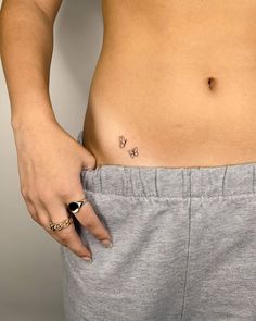 a woman's stomach with a small butterfly tattoo on her left side, and a gold ring in the middle