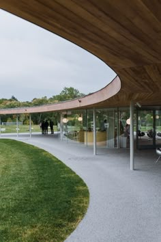 an outdoor area with grass and people standing in the background, surrounded by glass walls