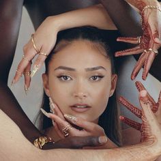 a woman is holding her hands up to her face while wearing rings and bracelets