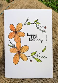 a handmade birthday card with orange flowers and green leaves on the front, sitting on a burlap surface