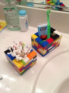 two legos are sitting on the bathroom sink counter with toothbrushes and toothpaste