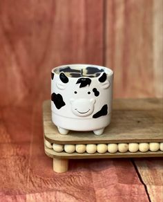 a ceramic cow sitting on top of a wooden stand