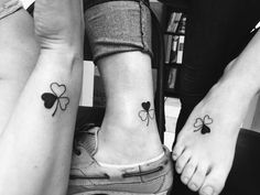 three people with matching tattoos on their feet, one has four clovers and the other has