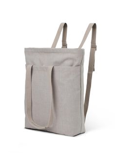 a gray bag with straps on the side and an open pocket at the bottom, in front of a white background