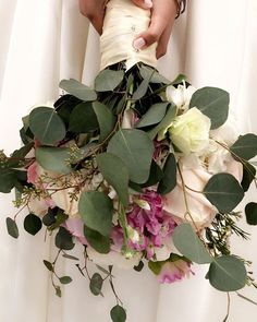 the bride's bouquet is made up of flowers and greenery