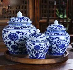 three blue and white vases sitting on top of a wooden tray next to each other