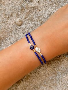 These evil eye bracelets are handmade-to-order just for you! 🧿 Evil eye jewelry dates as far back as 3000 BC. Many ancient cultures wore amulets or jewelry with the evil eye symbol to protect them. Today the evil eye brings good luck and good vibes. An evil eye in royal blue also represents inner peace, good karma and fate! Each one is made-to-order and features a handmade lampwork evil eye bead. Because the beads are handmade each one is unique and there may be slight variations in the size and shape.  From the drop-down menu you can choose between the evil eye bracelet, the shell bracelet, or both/set of two (as seen in photo #1).  The shell bracelet features genuine sea shells from Bali. Each shell is unique and hand chosen for its natural beauty.  🧿 Materials: Handmade Lampwork Evil Evil Eye Jewelry Bracelet, White Choker Necklace, Beaded Evil Eye, Bracelets Friendship, Eye Bracelets, Anklet Designs, Eye Symbol, Bracelet Stacking, Diy Friendship Bracelets Patterns