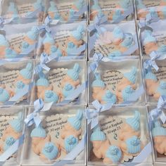 twelve baby shower cookies in boxes with blue ribbon and bows on them, all shaped like babies