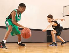 two young boys playing basketball on an indoor court