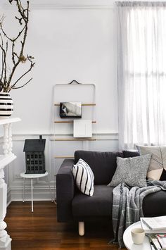 a living room with white walls and wood floors, black couches and coffee table