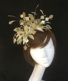 Gold Fascinator made to order from our UK studio and perfect for mother of the bride. This Fascinator design combines clusters of glass leaves, flowers , feathers and crystals which blend together in a stunning  bespoke display. The gold and mother of pearl colouring create a soft colour pallet which would work beautifully with both silver and gold tone outfits and is set on a fine comfort fit tiara band. As with all our designs, this piece can be made exact to the image or in any colour combina Whimsical Round Crown Headband For Wedding, Elegant Handmade Fascinator With Pinched Crown, Handmade Structured Crown Fascinator For Kentucky Derby, Handmade Fascinator For Kentucky Derby With Structured Crown, Gold Round Crown Headband For Wedding, Elegant Tall Crown Headband For Parties, Handmade Kentucky Derby Fascinator With Structured Crown, Elegant Party Headband With Tall Crown, Evening Headpiece With Handmade Flowers And Pinched Crown