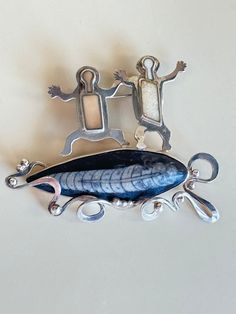 two metal figurines sitting on top of each other next to an object that looks like a fish