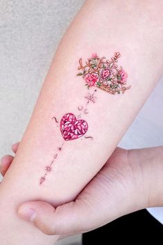 a woman's arm with a heart and flower tattoo on it