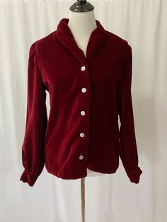 Unique and luxurious deep red handmade velvet blouse. A beautiful blouse to dress up or dress down. Wear this beauty on its own, over another blouse or a tee. It can be a jacket too. The thick velvet blouse is adorned with shell buttons. Condition: Excellent vintage condition. Size: Fits a small-medium. Please review measurements to ensure a proper fit. Mannequin is a women's size 4 for reference. Measurements: Taken when garment was flat and buttoned. Double bust and waist measurements. All sal Elegant Velvet Tops For Fall, Vintage Long Sleeve Padded Blouse, Vintage Padded Long Sleeve Blouse, Fitted Burgundy Shirt For Fall, Elegant Fitted Velvet Blouse, Elegant Velvet Blouse For Fall, Fitted Velvet Top For Formal Occasions, Elegant Long Sleeve Velvet Tops, Red Velvet Party Tops