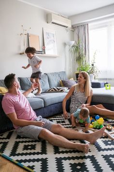 a family sitting on the floor in their living room playing with toys and smiling at each other